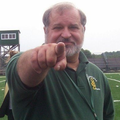 Mr. Gerald J. Carasea pointing at the camera on the football field